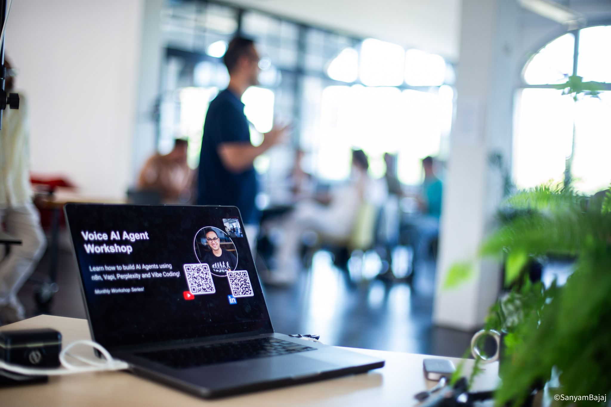 Voice AI Agent Workshop on a laptop, with Aemal teaching in the background